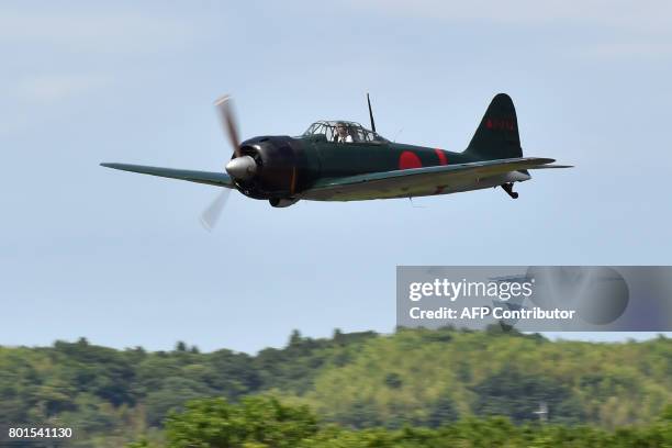 This picture taken on June 9, 2017 shows a restored World War II-era Mitsubishi A6M Type 22 Zero fighter flying over an airfield in Ryugasaki,...