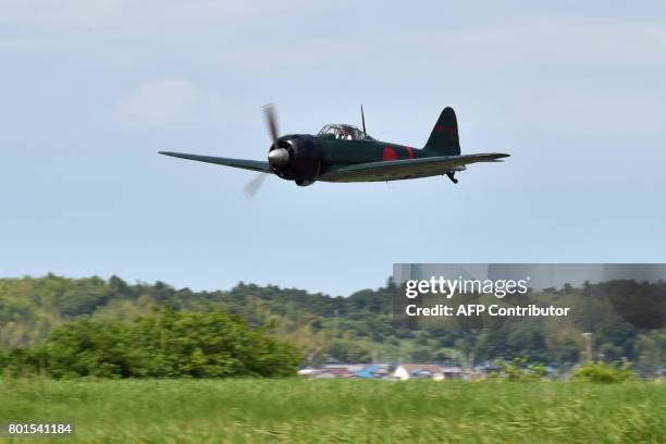 This picture taken on June 9, 2017 shows a restored World War II-era Mitsubishi A6M Type 22 Zero fighter flying over an airfield in Ryugasaki,...
