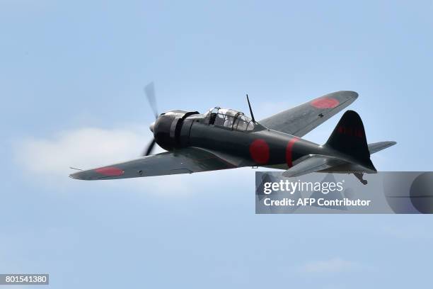 This picture taken on June 9, 2017 shows a restored World War II-era Mitsubishi A6M Type 22 Zero fighter flying over an airfield in Ryugasaki,...