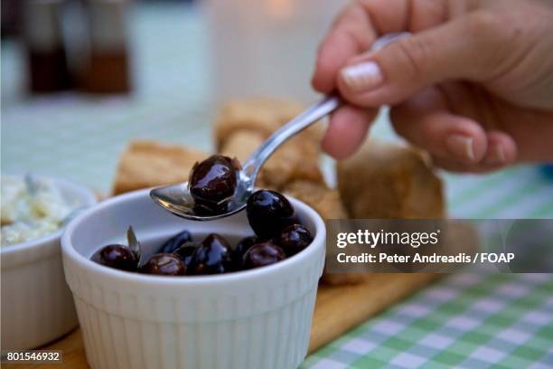 hand holding spoon with olives - kalamata olive fotografías e imágenes de stock