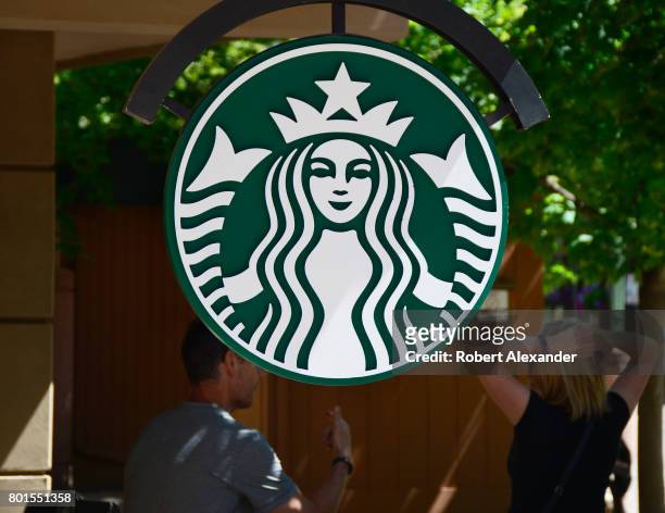 Sign embellished with the Starbucks logo hangs near the entrance to the Starbucks coffee shop in Aspen, Colorado. The coffeehouse chain is...