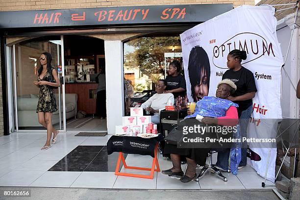 Dorah Mtetwa , age 22, a university student, talks to a friend on her mobile phone while visiting a beauty salon to do her nails on May 12, 2007 in...