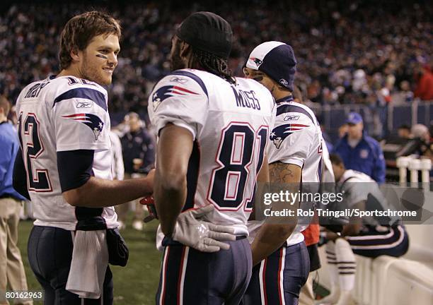 Tom Brady of the New England Patriots and Randy Moss look on from the bench against the New York Giants during their game on December 29, 2007 at...
