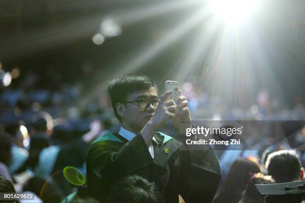 Students takes photos by his smartphone during the graduation ceremony of Shantou University on June 27, 2017 in Shantou, China.