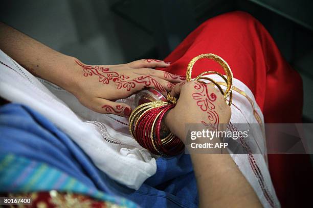 Bangladeshi bride plays with her bracelets while waiting for her makeup to be finished, at a beauty salon in Dhaka, on March 8 on the occasion of the...