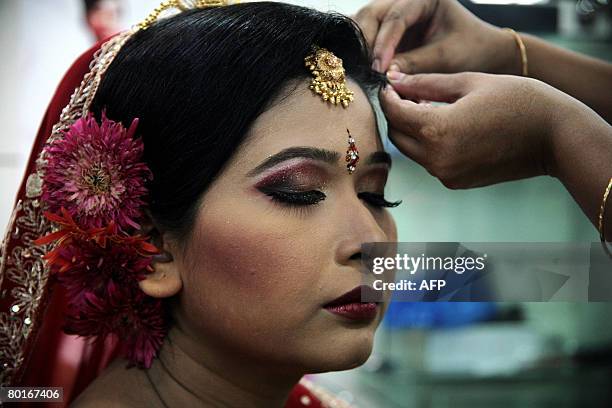 Bangladeshi woman fixes the head decorations of a young bride, at a beauty salon in Dhaka, on March 8 on the occasion of the International Womens'...