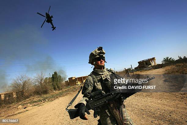 Soldier from 2nd Battalion 23rd Infantry Regiment, patrols as a US military attack helicopter flies overhead in the restive Diyala province,...