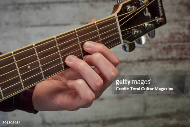 Detail of a guitarist playing an open D chord on an acoustic guitar, taken on November 24, 2016.