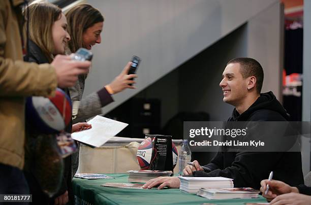 Fan shows Sasha Pavlovic of the Cleveland Cavaliers the picture she just took of him while he signs an autograph for a donated children's book to...