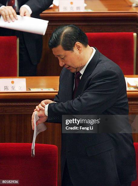 Xi Jinping, member of the Politburo Standing Committee, looks at his watch at the end of the third plenary session of the National People's Congress,...