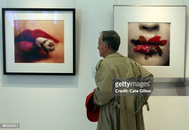 Man views photographs 'Cigarette and Lips, before 1961' and 'Mouth for L'Oreal, New York, 1986' both by Iriving Penn on 10 March, 2008 in London,...