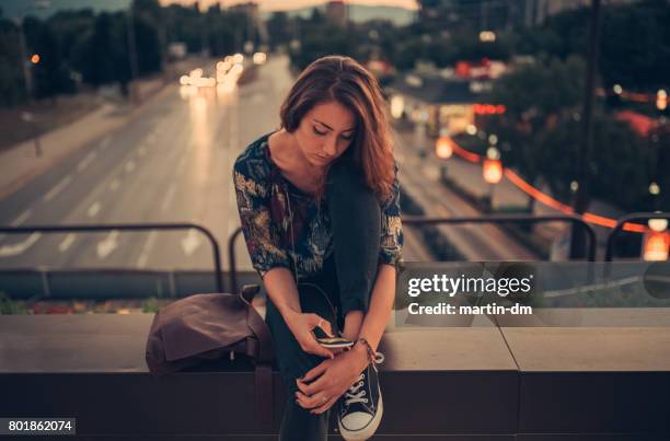 depressed teenage girl texting on the bridge - stress emotivo imagens e fotografias de stock