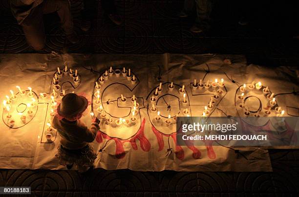 Palestinian child lights a candle during a Hamas rally in Gaza City against the Israeli blockade of the Gaza Strip and air strikes on the Hamas-run...