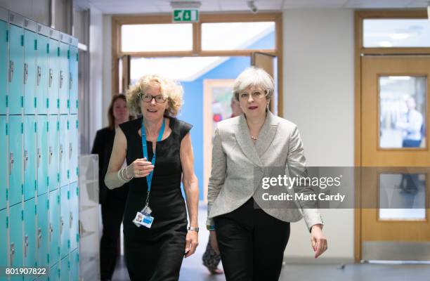 Prime Minister Theresa May walks with head teacher Dr Helen Holman after she sat in on a session for teachers receiving training in mental health...