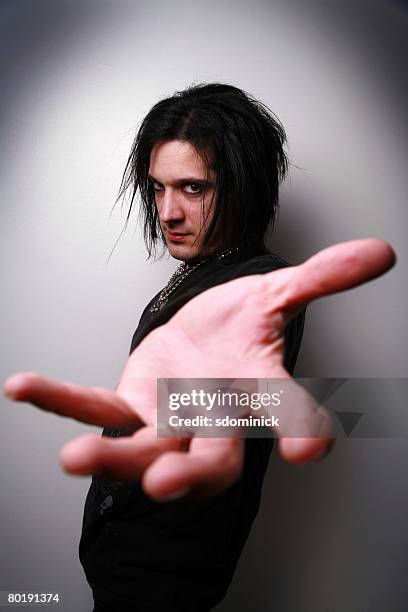 a man with an edgy rocker look reaching out his hand. - emo guy stock pictures, royalty-free photos & images