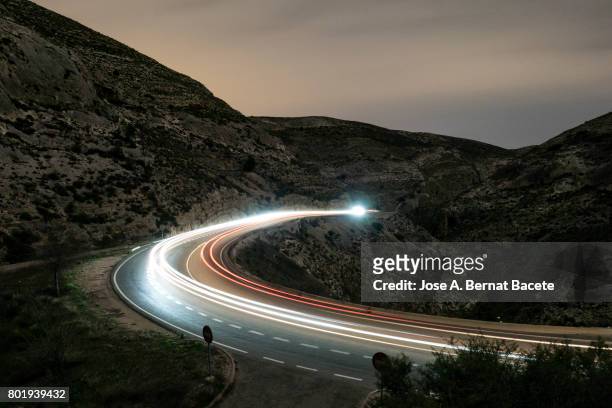lights of vehicles circulating along a road of mountain with curves closed in the night - long exposure car stock pictures, royalty-free photos & images