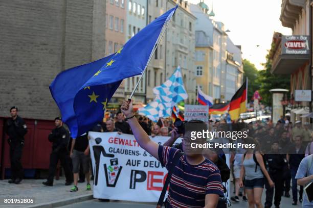 Counter-protester carries EU-flag. Today around 50 people joined the racist Pegida march in Munich. Police took in custody several...