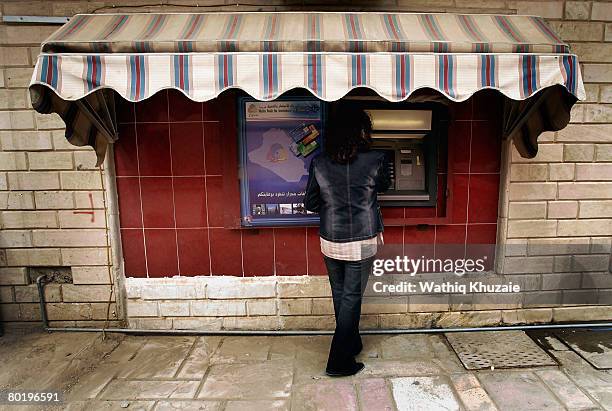 An Iraqi employee of Warka Bank for Investment and Finance shows how to use credit/debit cards machine on March 11, 2008 in Baghdad, Iraq. Warka Bank...