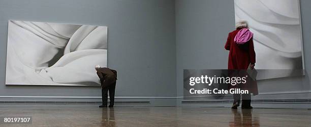 Gentleman takes a close look at the painting 'Phantom' while a lady views Alison Watt's oil on canvas painting 'Vowel' on March 11, 2008 in London,...
