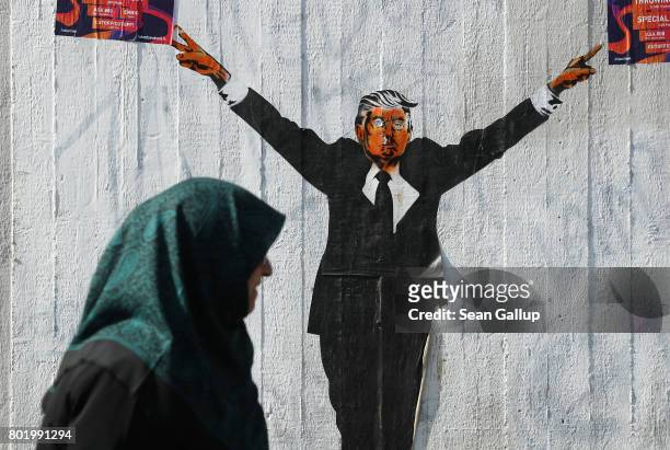 Muslim woman walks past a street artist's rendition of U.S. President Donald Trump on June 27, 2017 in Berlin, Germany. The U.S. Supreme Court...