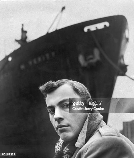 Portrait of American author Gore Vidal as he poses beneath the bow of a large ship, April 1947.