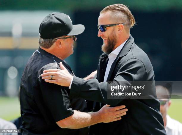 Former Chicago White Sox pitcher Mark Buehrle hugs pitching coach Don Cooper during the ceremony to retire his number, #56, before the game between...