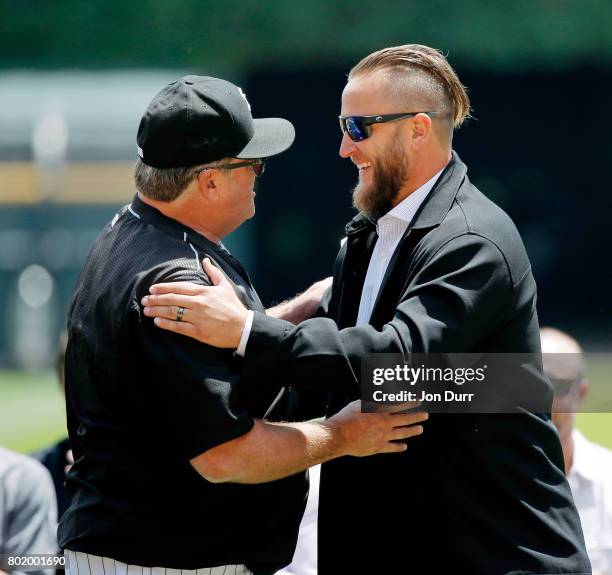 Former Chicago White Sox pitcher Mark Buehrle hugs pitching coach Don Cooper during the ceremony to retire his number, #56, before the game between...