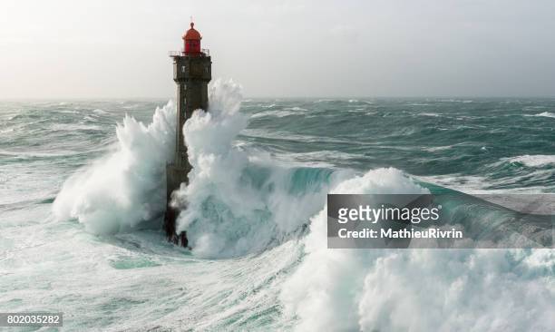 begining of an amazing wave on la jument lighthouse - burrasca fotografías e imágenes de stock