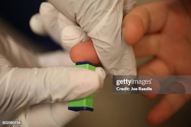 Medical assistant uses a pin prick to draw blood from a patient on National HIV Testing Day at a Planned Parenthood health center on June 27, 2017 in...