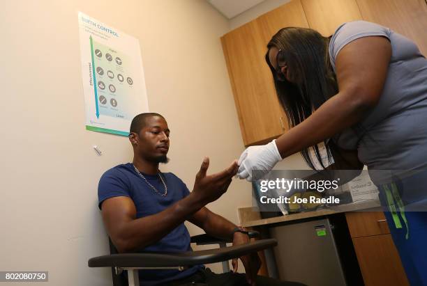 Jamal Wilson has blood drawn from a finger as he receives a free HIV test from a medical assistant on National HIV Testing Day at a Planned...