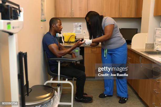 Jamal Wilson has blood drawn from a finger as he receives a free HIV test from a medical assistant on National HIV Testing Day at a Planned...