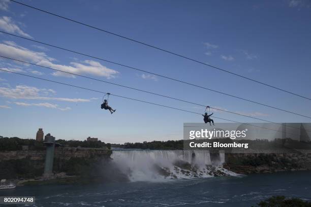 Tourists zipline past the American Falls, center, and the Bridal Veil Falls, right, in Niagara Falls, Ontario, Canada, on Wednesday, June 21, 2017....