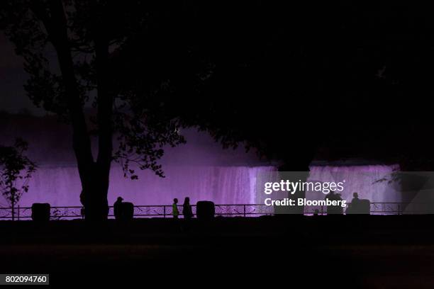 The silhouettes of tourists are seen near the illuminated Horseshoe Falls at night in Niagara Falls, Ontario, Canada, on Wednesday, June 21, 2017....