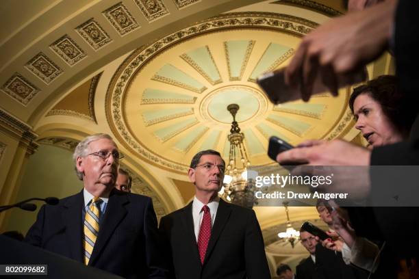 Senate Majority Leader Mitch McConnell listens to a question as Sen. John Barrasso looks on during a press conference after a closed-door Senate GOP...