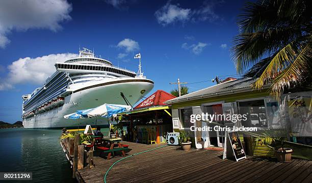 Fishermen tie up their wooden boat next to a cruise liner in St John's Harbour on March 10, 2008 in St John's Antigua. In high season up to five...