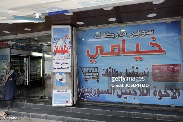 Poster, that welcomes holders of the World Food Programme electronic cards, is seen on the window of Khiami grocery store, which accepts the United...