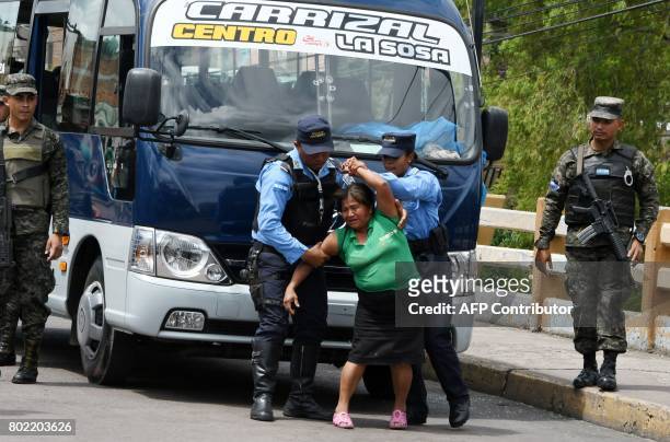 Police officers try to control a woman whose son, a bus driver, was killed by gang members for refusing to pay them a "war tax", over Soberania...