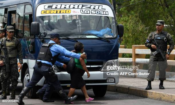 Police officers try to control a woman whose son, a bus driver, was killed by gang members for refusing to pay them a "war tax", over Soberania...
