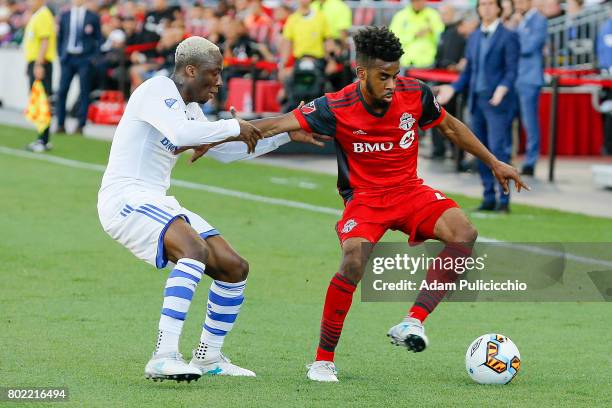 Midfielder Raheem Edwards of Toronto FC fights for control of the ball as Midfielder Ballou Jean-Yves Tabla of the Montreal Impact grabs his arm...