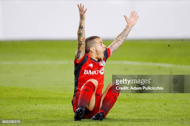 Forward Sebastian Giovinco of Toronto FC raises his arms and yells for a whistle after being tackled hard to the ground against the Montreal Impact...