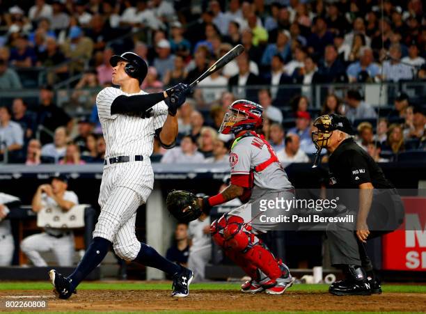 Aaron Judge of the New York Yankees hits a home run as catcher Martin Maldonado of the Los Angeles Angels and umpire Larry Vanover watch in the 5th...