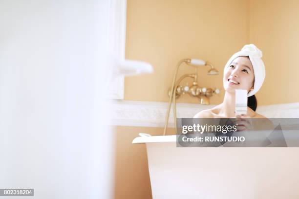 woman using smart phone in bathtub - baignoire sur pieds photos et images de collection