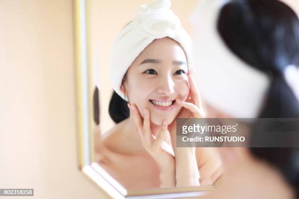 woman touching face in mirror - body care and beauty stock pictures, royalty-free photos & images