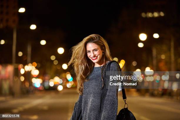 portrait of happy woman on road in city at night - tossing hair facing camera woman outdoors stock pictures, royalty-free photos & images
