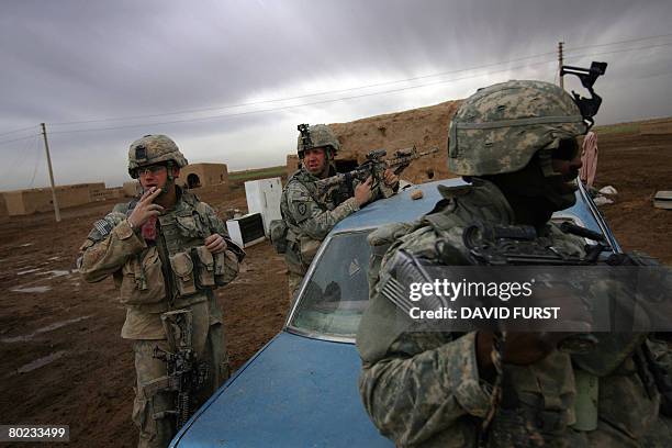 Soldiers from Ghostrider Company 3rd Squadron 2nd Stryker Cavalry Regiment rest around a car during an operation to investigate sectarian violence...