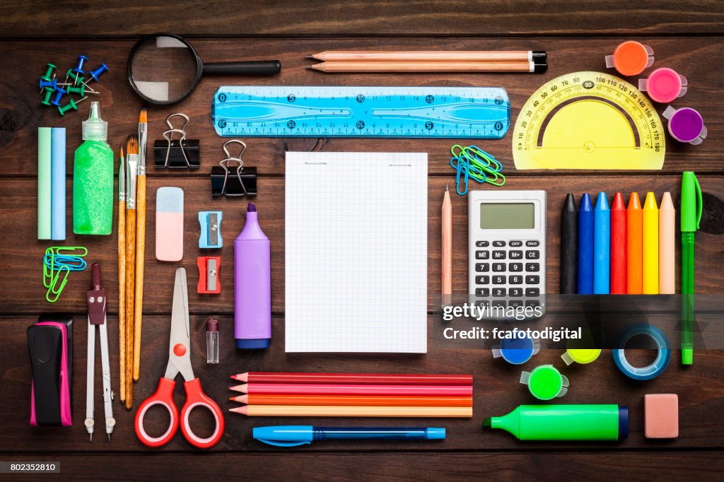 Top view of a large group of school or office supplies on wooden table