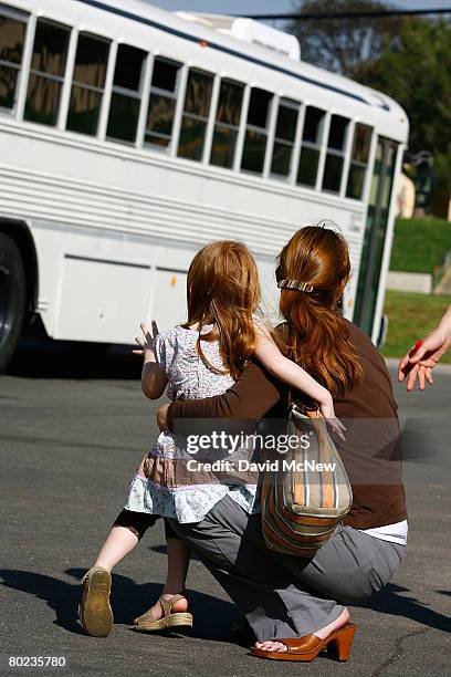 Anne Everett, who is due to give birth in six weeks, and her three-year-old daughter Aubrey wave good-bye to the bus carrying her husband Capt Ben...
