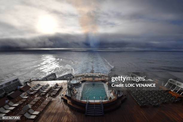 Employees prepare sunbeds on a deck aboard the British cruise liner RMS Queen Mary 2 on June 26, 2017 as it sails in the Atlantic ocean during The...