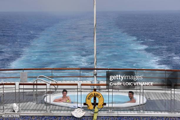 Passengers enjoy a jacuzzi aboard the British cruise liner RMS Queen Mary 2 on June 26, 2017 as it sails in the Atlantic ocean during The Bridge...