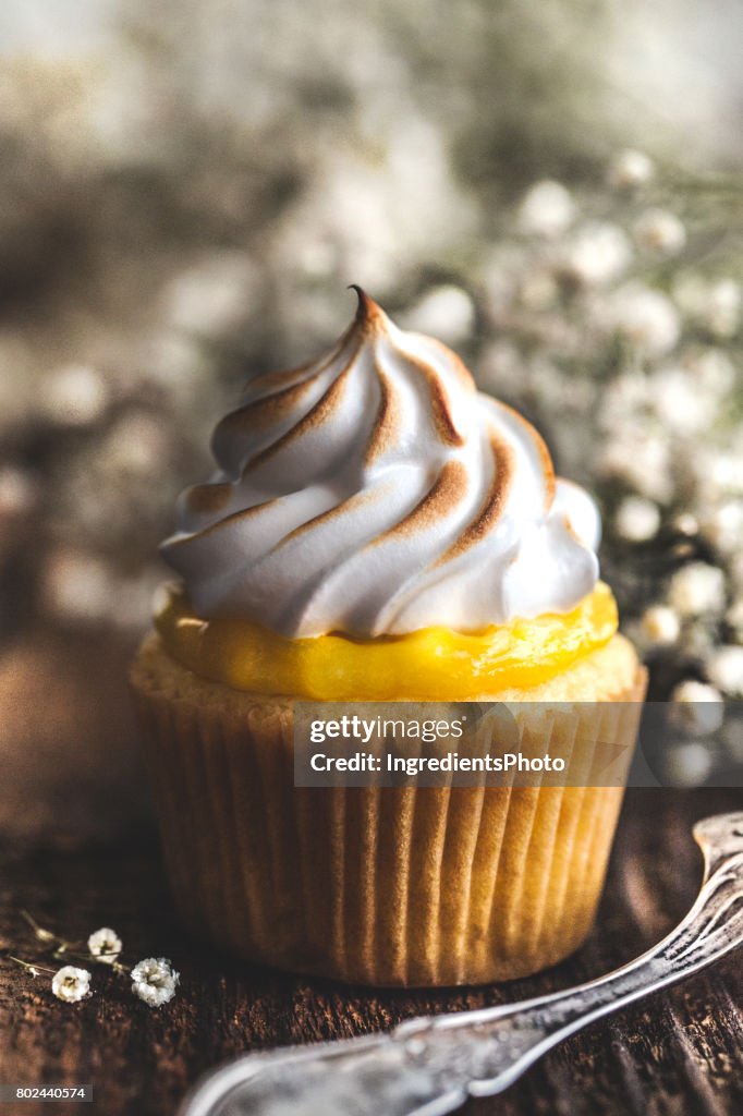 Queque de merengue de limão em uma mesa de madeira rústica.